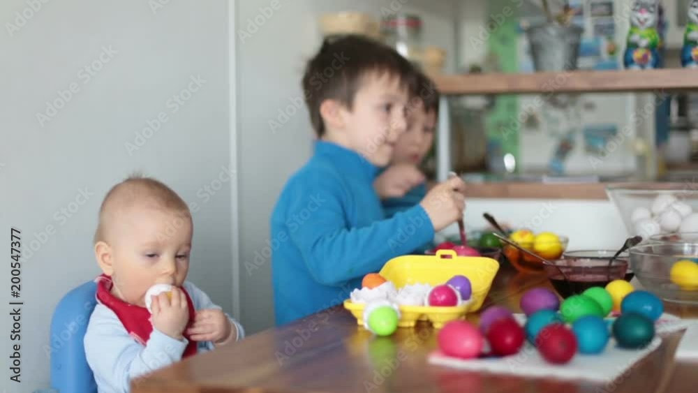 Three children, coloring and painting easter eggs at home for the holiday Three children, coloring and painting easter eggs at home for the holiday