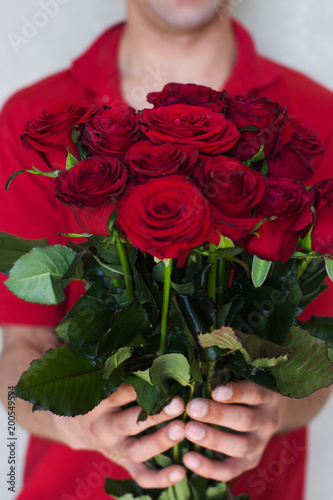 Fototapeta Naklejka Na Ścianę i Meble -  A man close-up gives a bouquet of red roses.