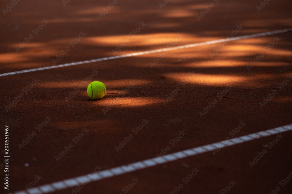 Tennis ball on a court between lines and spots of light