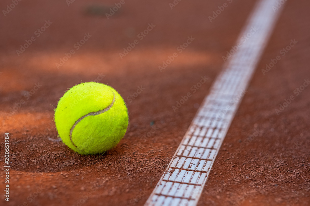Closeup of one tennis ball close to a white line on a slug court