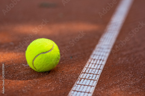Closeup of one tennis ball close to a white line on a slug court © Andrei