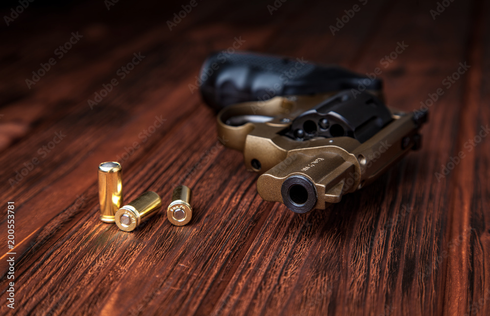 Obraz premium pistol and cartridges on a wooden background