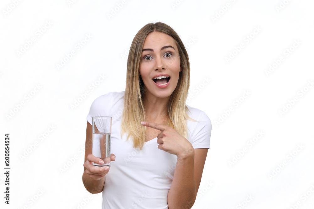 Hübsche blonde Frau zeigt begeistert auf ein Wasserglas in ihrer hand Hübsche blonde Frau zeigt begeistert auf ein Wasserglas in ihrer hand