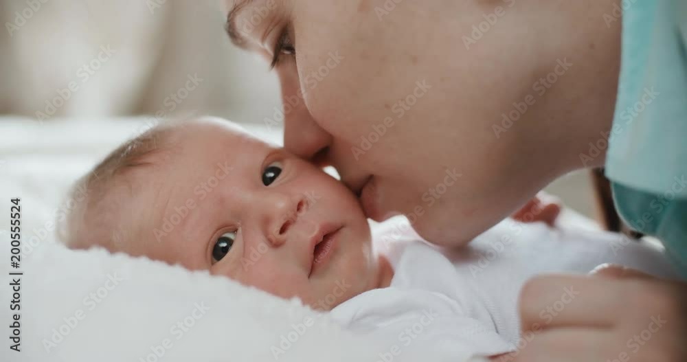 4k.Happy mother and her newborn baby, kissing her child. Resting in bed together. Maternity concept. Parenthood. Motherhood Beautiful Happy Family Slow Motion 4k.Happy mother and her newborn baby, kissing her child. Resting in bed together. Maternity concept. Parenthood. Motherhood Beautiful Happy Family Slow Motion