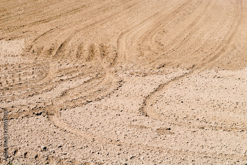Plowed field. Drawing on the ground furrows and traces of tractor tires