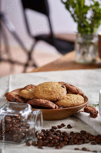 Roasted coffee beans get out of overturned glass jar on homespun tablecloth, selective focus, side view photo