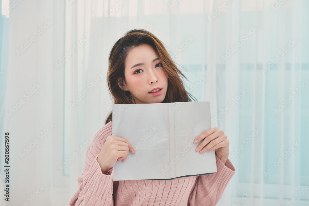education Winter Concept. Cute Asian girl in winter dress. Beautiful woman is relaxing in a white bedroom. Beautiful women in winterwear are studying in the bedroom. education Winter Concept. Cute Asian girl in winter dress. Beautiful woman is relaxing in a white bedroom. Beautiful women in winterwear are studying in the bedroom.
