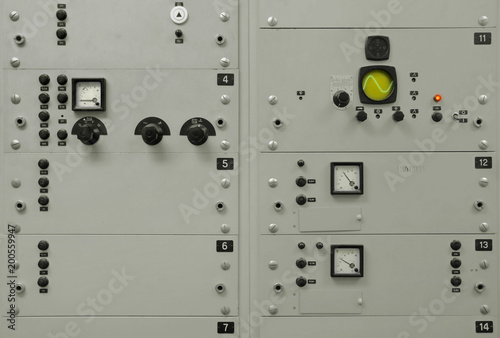 Old, grey electrical control panel with buttons, switches, fuses, plugs, monitors and numbers, and with some copyspace