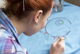 Photo of girl who drawing acrylic paints on blue clothes