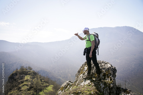 Successful young hiker resting in the forest and enjoying his adventure time