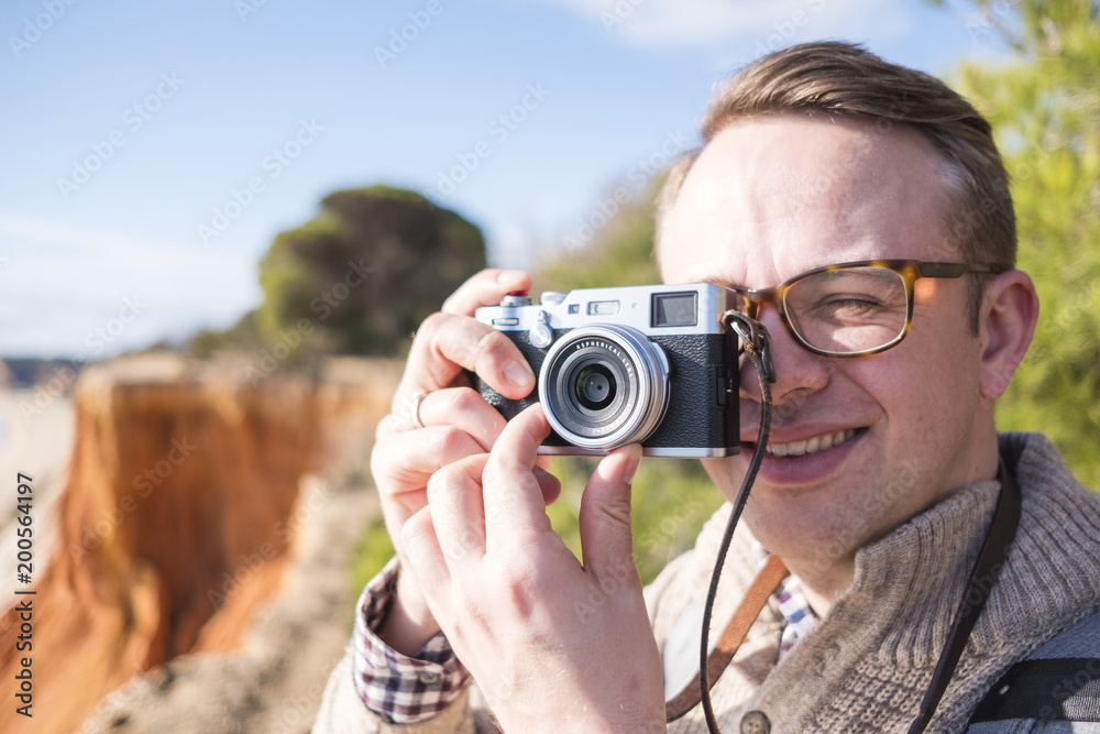 A photographer taking pictures of cliffs and ocean during sunny day A photographer taking pictures of cliffs and ocean during sunny day