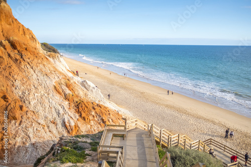 People walking on Falesia Beach with beautiful cliffs in Algarve, Portugal