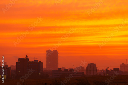 Last rays of sun at sunset over a tall city buildings