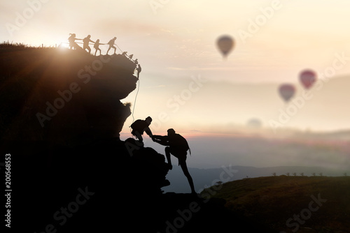 Male and female hikers climbing up silhouette mountain cliff . teamwork ,success ,helps , business concept. 