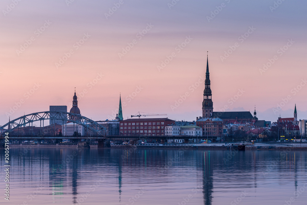 Night view on the illuminated riverside with reflection on the river in Riga