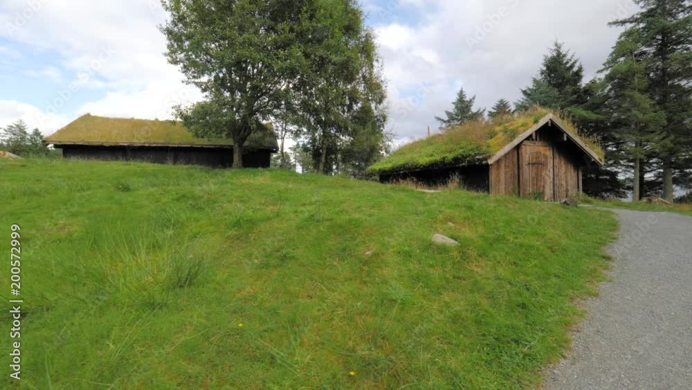 Norway grass cabin. Someone or tourist examines an ancient village in Norway, approaching the front door of the house. Rural house in the middle of great scenery of Norwegian fjord on summer sunny day Norway grass cabin. Someone or tourist examines an ancient village in Norway, approaching the front door of the house. Rural house in the middle of great scenery of Norwegian fjord on summer sunny day