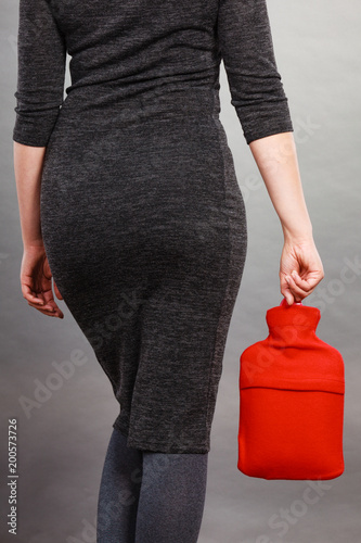 Woman holding warm red hot water bottle