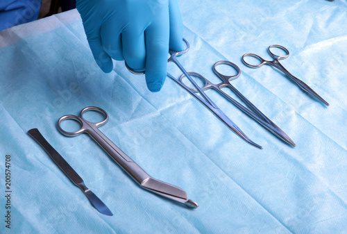 Detail shot of sterilized surgery instruments with a hand grabbing a tool ,