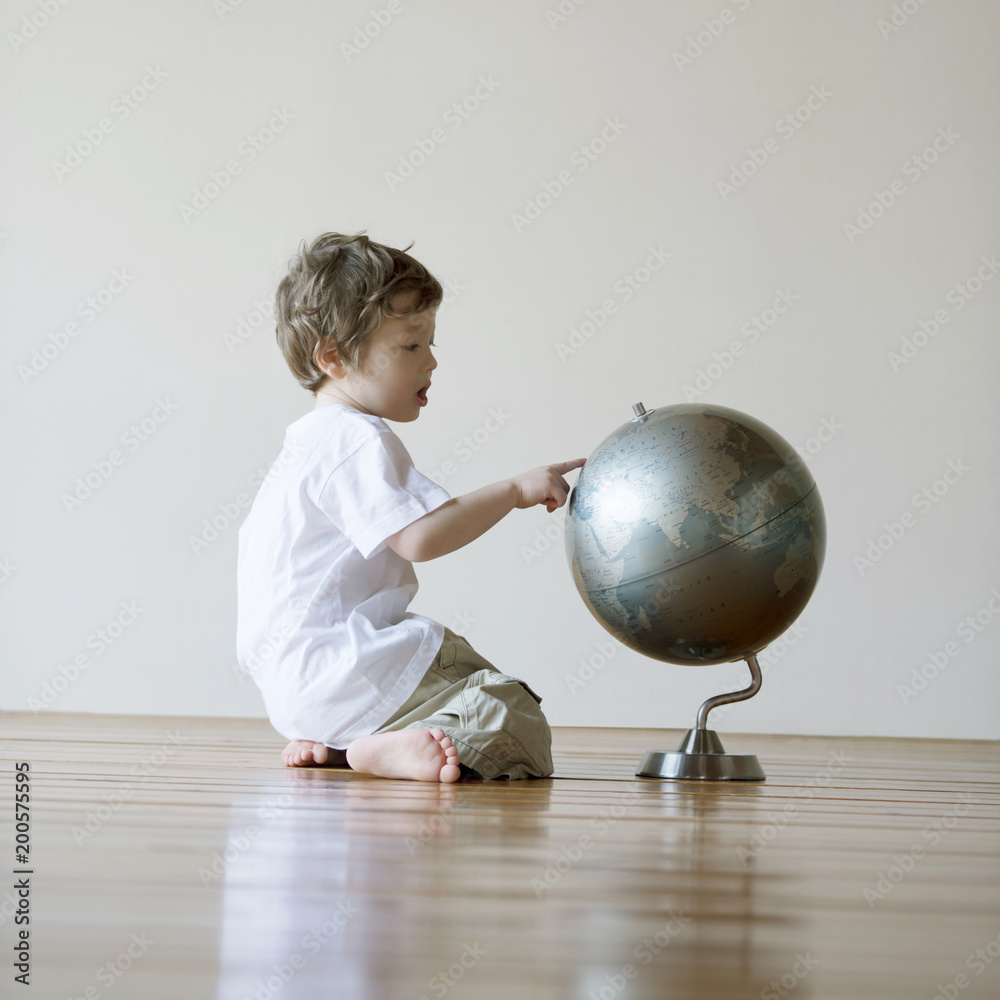 Boy looking at globe while sitting at home Boy looking at globe while sitting at home