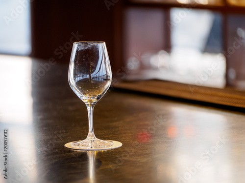 Close-up detail of an empty wine glass with smudged rims and multiple reflections on a coaster and wooden bar counter. Shallow depth of field. Kyoto, Japan. Travel and party concept.