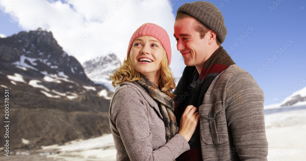 Girlfriend wrapping scarf around boyfriend playfully outside in the snow