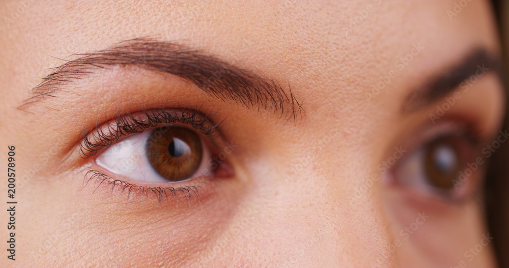 Fototapeta premium Extreme close up of female millennial's eyes blinking looking off camera