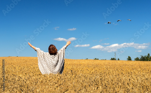 Happy farmer among ripe harvesting field of wheat. Concept of reach agricultu...
