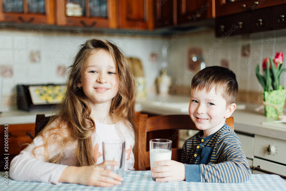 Children drink milk in the kitchen at the morning Children drink milk in the kitchen at the morning
