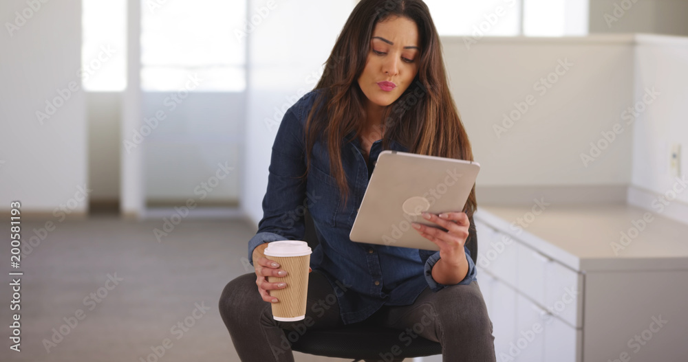 Professional female sitting in desk chair using tablet then walking off camera Professional female sitting in desk chair using tablet then walking off camera