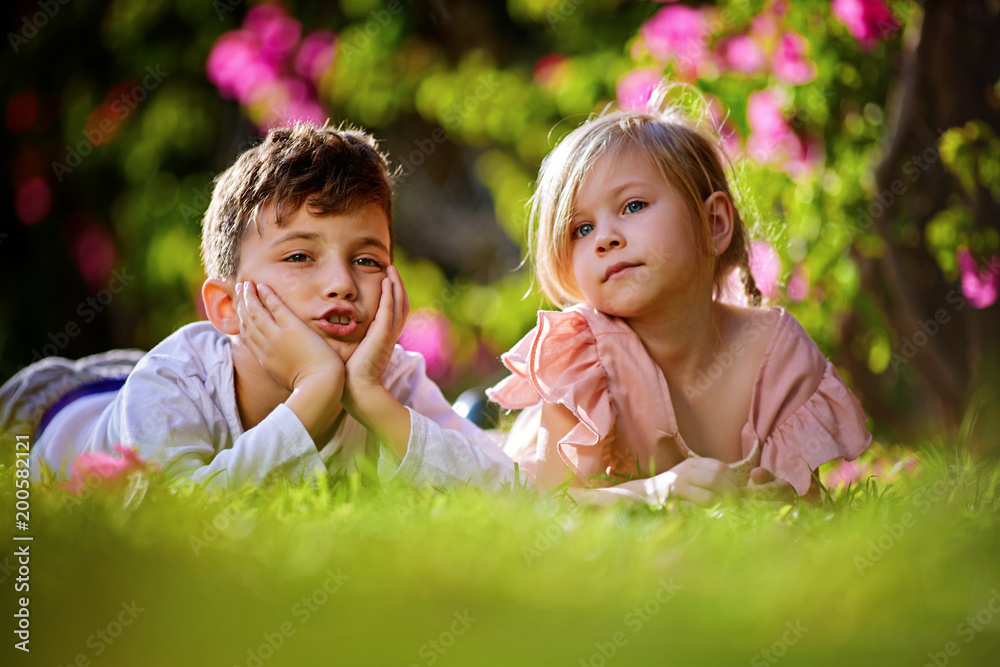Kids, boy and girl playing, joking, hogging and having fun at sunset in the park on the green grass. Children's games, leisure Kids, boy and girl playing, joking, hogging and having fun at sunset in the park on the green grass. Children's games, leisure