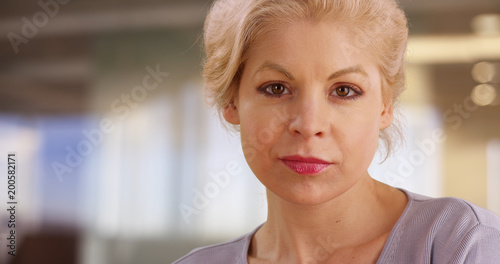 Close up of successful female removing glasses looking at camera with confident expression
