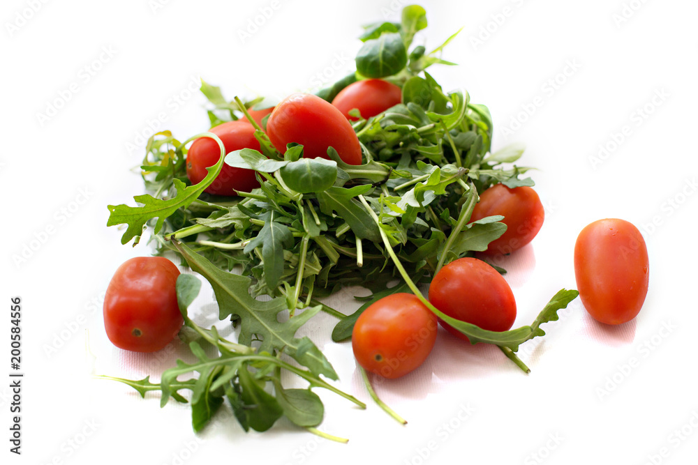 Green arugula salad and red tomatoes on white background Green arugula salad and red tomatoes on white background