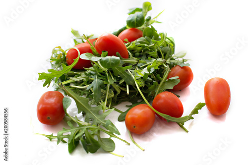 Green arugula salad and red tomatoes on white background