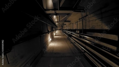 The cabin moves down in an elevator shaft. The view is directed downwards. The camera is moving. The lights in the shaft give the ride its own rhythm.