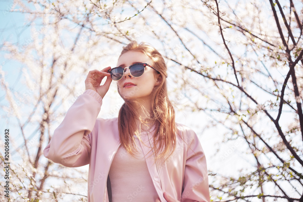 Spring fashion girl outdoors portrait in blooming trees. Beauty Romantic woman in flowers in sunglasses. Sensual Lady. Beautiful Woman Enjoying Spring Nature and fantasy orchard. Blossom girl. Pink . Spring fashion girl outdoors portrait in blooming trees. Beauty Romantic woman in flowers in sunglasses. Sensual Lady. Beautiful Woman Enjoying Spring Nature and fantasy orchard. Blossom girl. Pink .