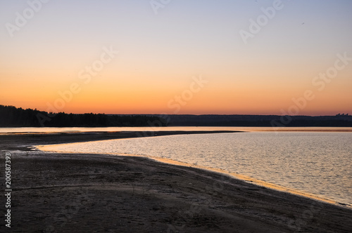 Tranquil nature scene. Sunset dawn sky above the sandy beach and water surface of the river Ob in soft evening colors. Altai, Russia.