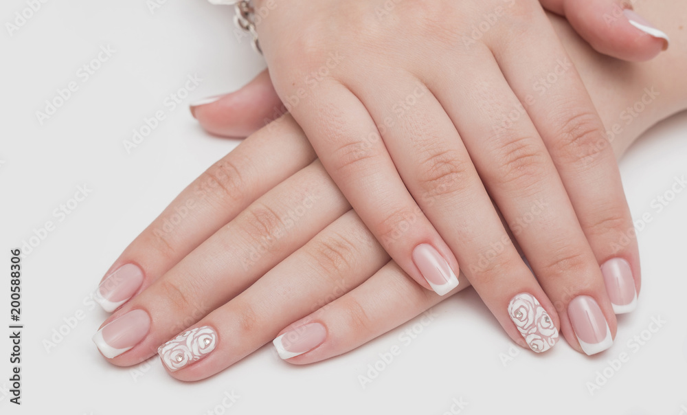 Manicure with rhinestones in the shape of hearts and pink balls on white and red nail Polish on a white background.