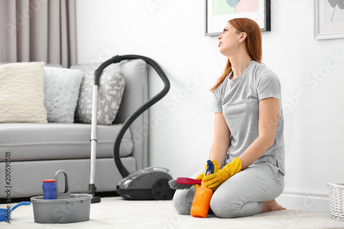 Tired housewife cleaning carpet at home