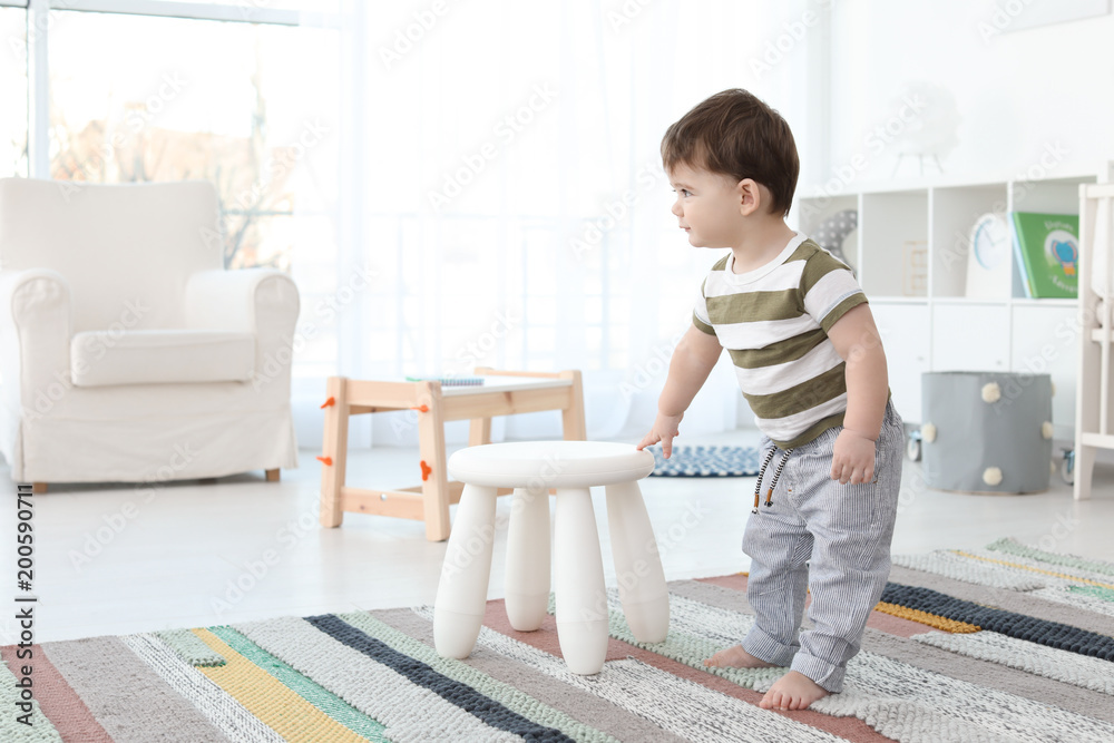 Cute baby holding on to stool at home. Learning to walk Stock Photo ...