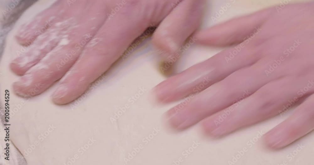 Close up of a pizza chef's hands kneading the dough to prepare a gourmet pizza and spreads the tomato sauce. Concept of: italianità, food, tradition. Close up of a pizza chef's hands kneading the dough to prepare a gourmet pizza and spreads the tomato sauce. Concept of: italianità, food, tradition.