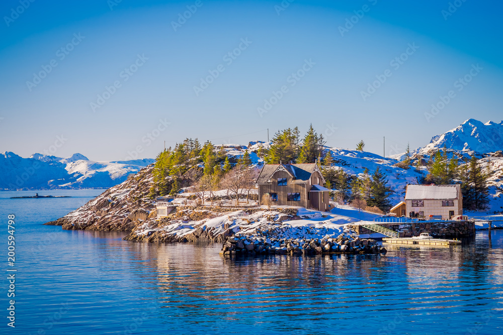 Beautiful outdoor view of wooden buildings on a rock in a seaside during a gorgeous blue sky in Lofoten Islands, Svolvaer