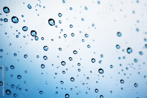 Drops of rain on glass with blue towhite background