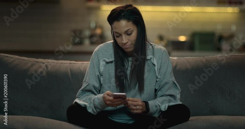 Woman sitting on a sofa in a cozy living texting her friends