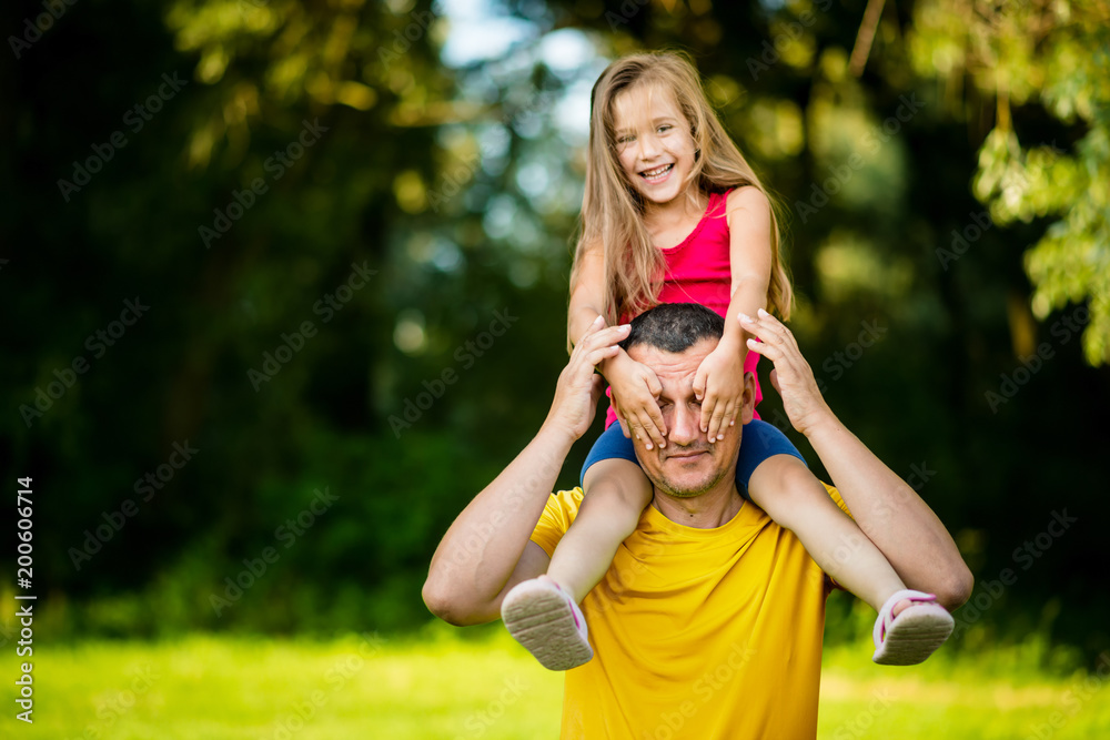 Father carrying carefree little daughter on shoulders Father carrying carefree little daughter on shoulders
