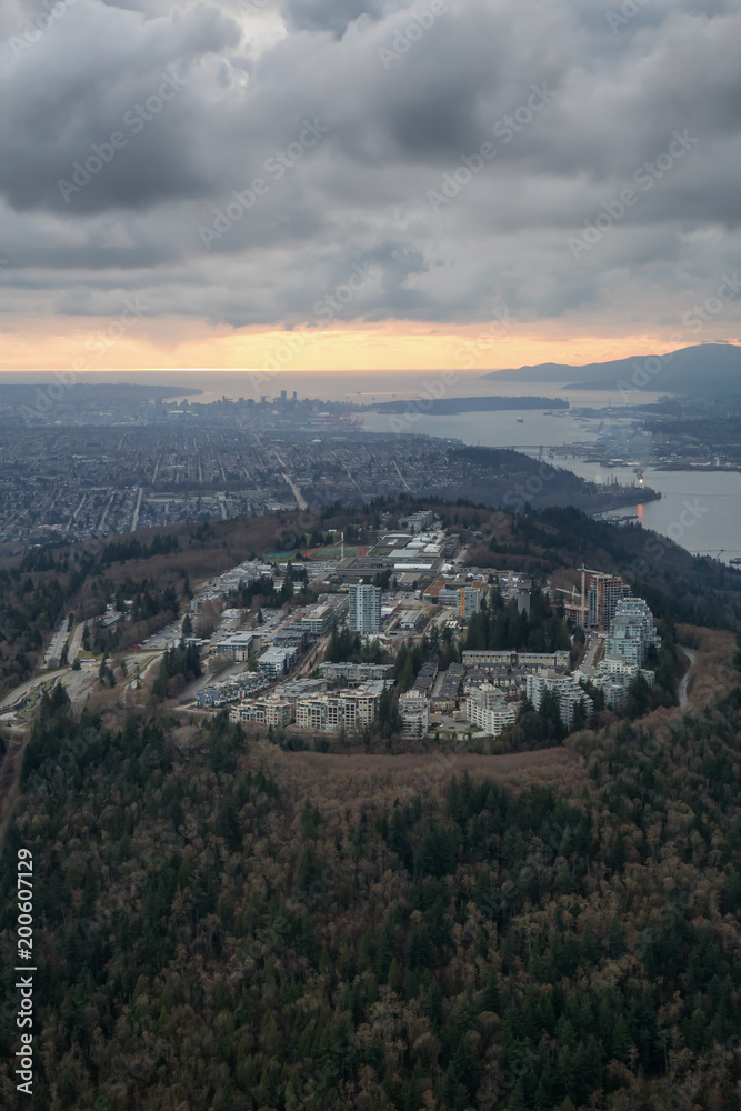 Striking Aerial view of Burnaby Mountain during a  dramatic cloudy sunset. Taken in Vancouver, British Columbia, Canada.