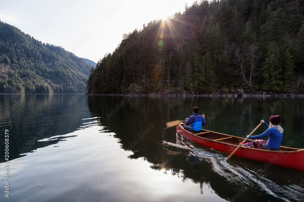 Couple friends canoeing on a wooden canoe during a sunny day. Taken in Harrison River, East of Vancouver, British Columbia, Canada.