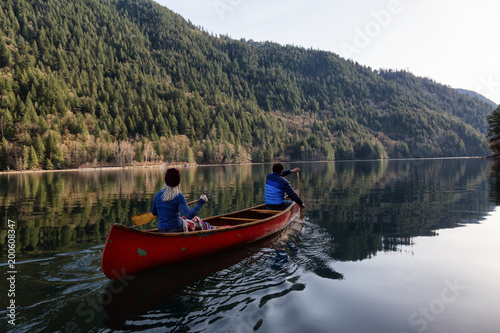 Couple friends canoeing on a wooden canoe during a sunny day. Taken in Harrison River  East of Vancouver  British Columbia  Canada.