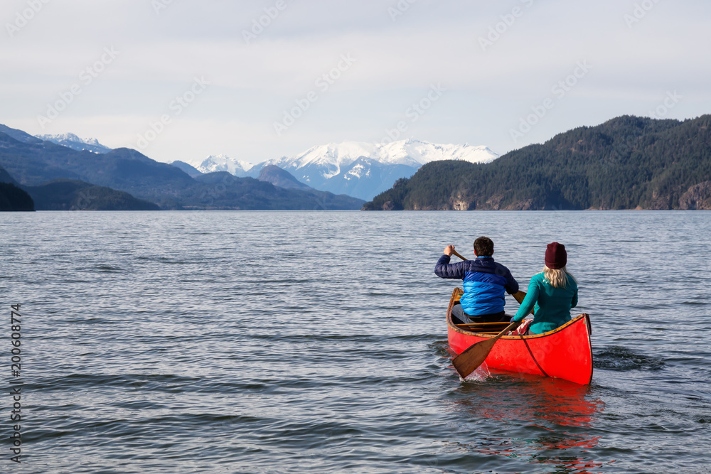 Naklejka premium Couple friends canoeing on a wooden canoe during a sunny day. Taken in Harrison Lake, East of Vancouver, British Columbia, Canada.