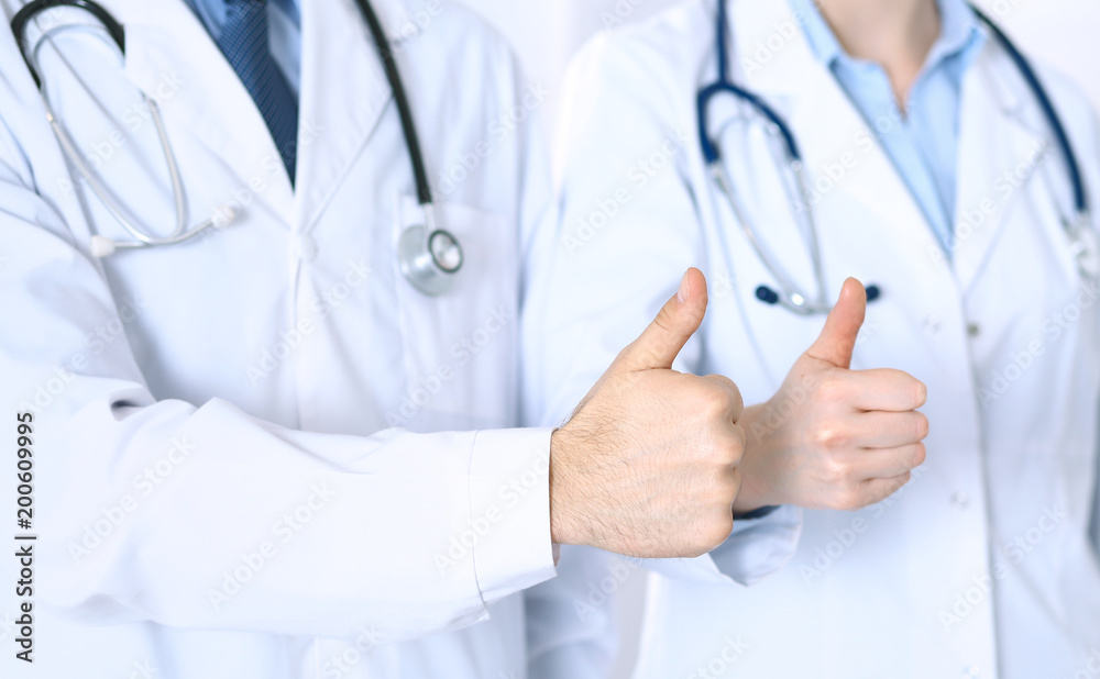 Team of unknown medicine doctors showing OK sign with thumb up close up. Success and high level service in health care, best treatment and customer loyalty and physical concept Team of unknown medicine doctors showing OK sign with thumb up close up. Success and high level service in health care, best treatment and customer loyalty and physical concept
