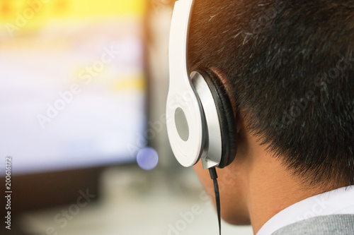 Education e-learning foreign languages Concept : Student Young man wearing Headphones listening English songs music and searching for learning abroad in classroon of university